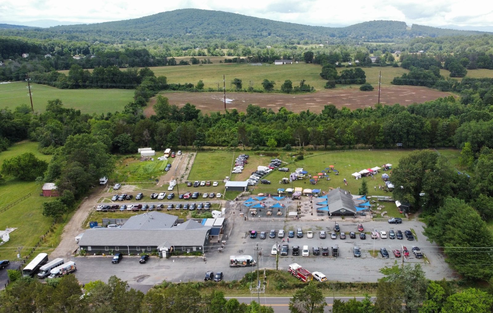 Patch Brewing Co. from the air on an event day: the ball field, the pavilion, tents and a full lot, with the Blue Ridge behind