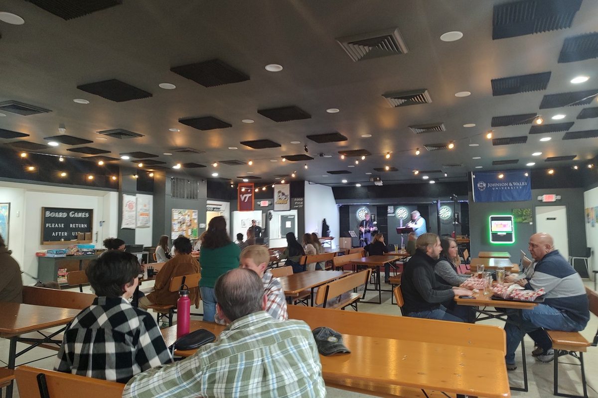 The taproom with a two-piece band playing at the far end, guests at long tables